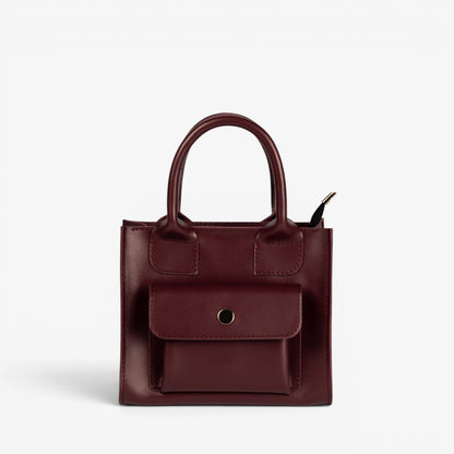Pache Sigil mini tote bag in deep burgundy smooth leather with a structured shape and front pocket. Adjustable strap for shoulder or crossbody wear.